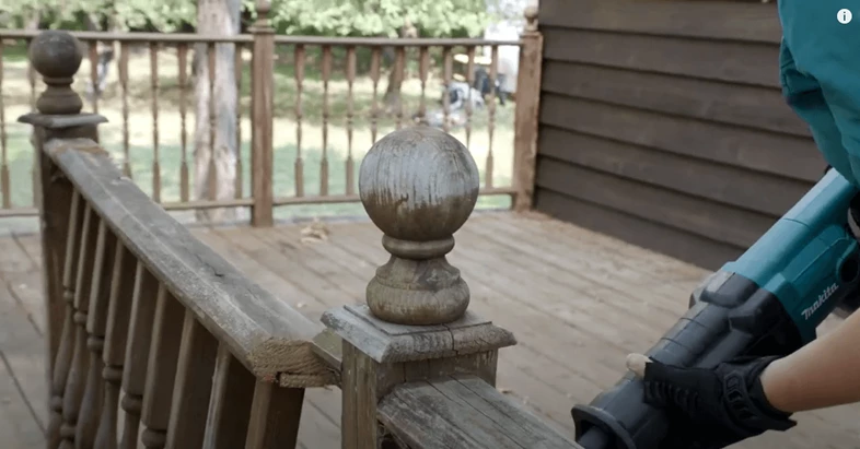 Person using a reciprocating saw to cut the railing off a deck